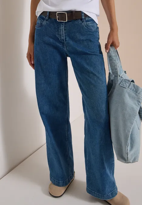 Ceinture Basic à boucle carrée Dark Brown Person trägt weite blaue Jeans mit Gürtel und hält eine hellblaue Jeans-Tasche.