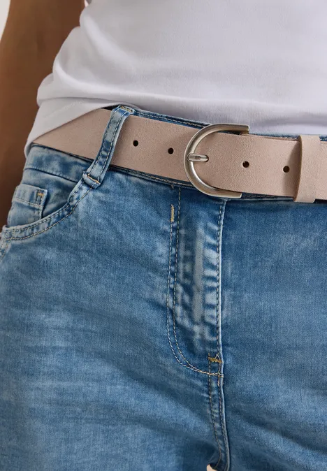 Ceinture avec détails métalliques Suede Beige Taillenansicht: hellbeiger Gürtel mit silberner Schnalle über blauen Jeans und weißem Oberteil.