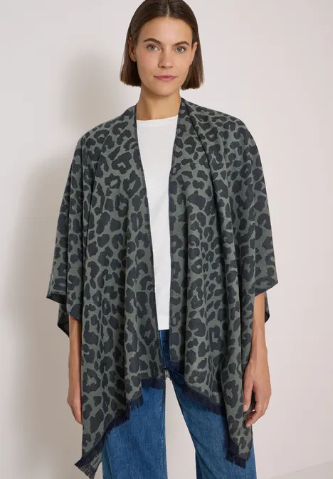 Frau in weißem Shirt und Jeans trägt offen fallenden dunkelgrünen Cardigan mit Leopardenmuster.