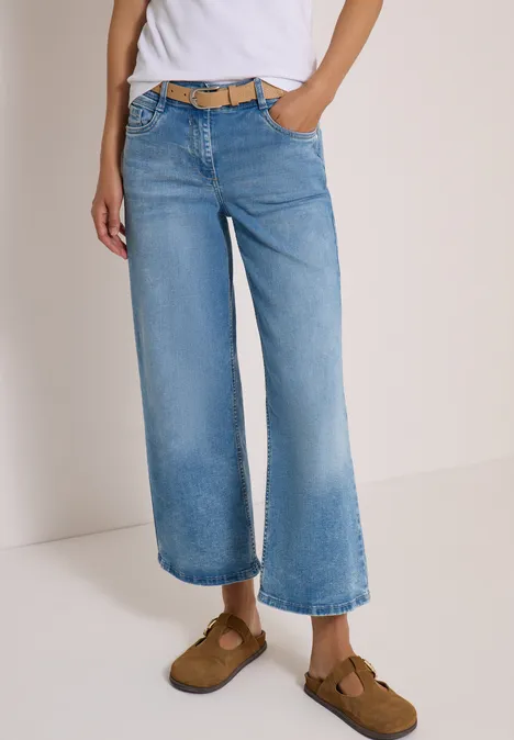 Person trägt helle, weitem Bein geschnittene Culotte-Jeans, Gürtel und braune Mokassins.