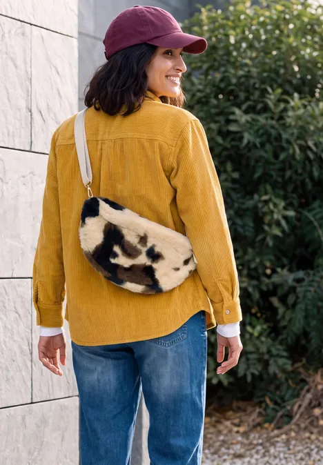 sac à bandoulière pearl beige Femme en chemise jaune et jean, casquette rouge, sac à bandoulière imprimé vache.