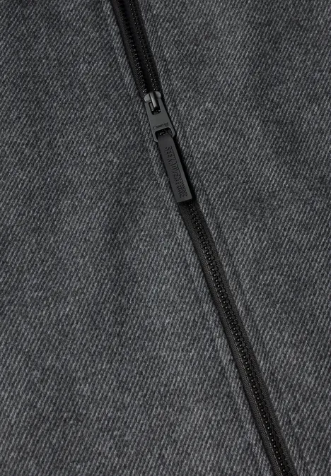 Close-up van een zwarte rits op donkergrijze stof.