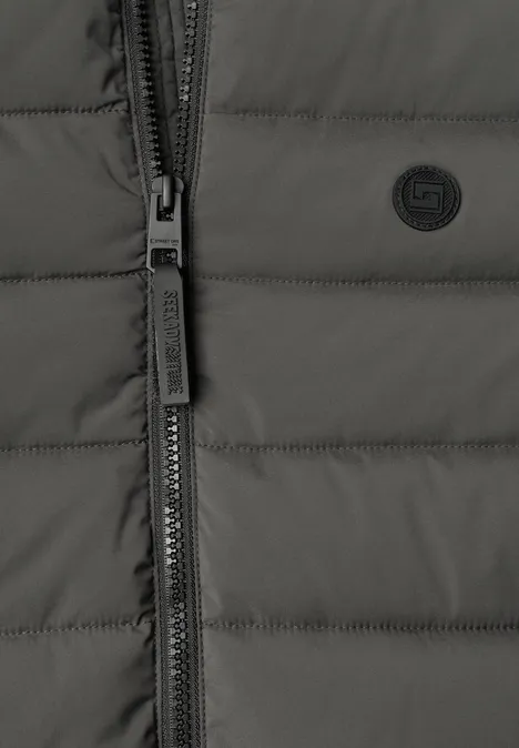 Nahaufnahme einer dunkelgrauen Steppjacke mit Reißverschluss und kleinem Logo