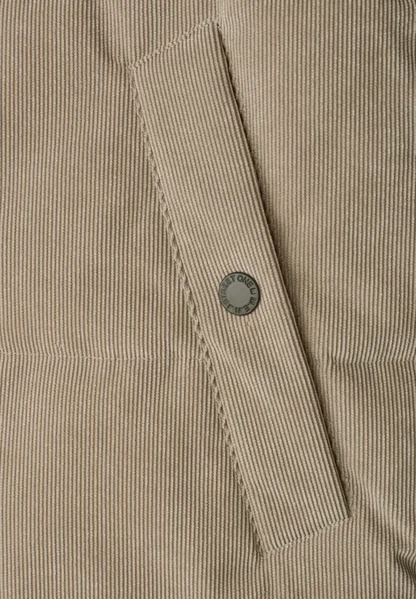 Hellbeiges Corduroy-Gewebe mit aufgesetzter Tasche und metallischem Druckknopf.
