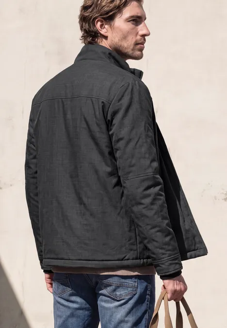 Un homme de dos porte une veste grise et un jean, tenant ses clés à la main.