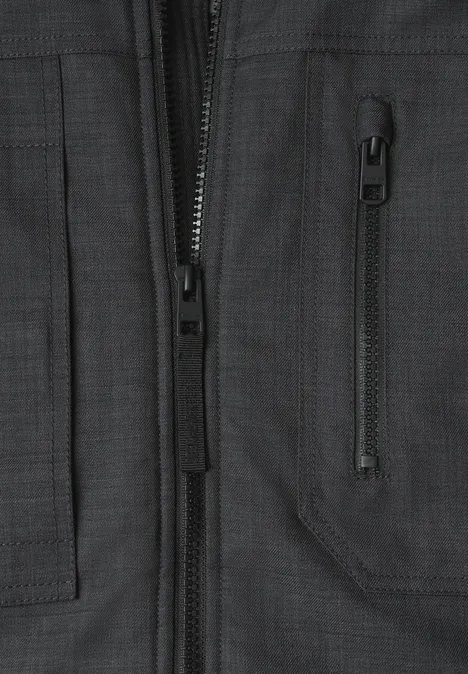 Vue rapprochée d'une veste noire, fermeture éclair visible et poche à soufflet oblique.