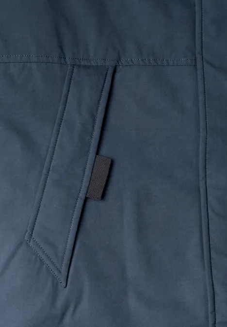 Gros plan sur une poche de veste bleu marine avec un onglet noir