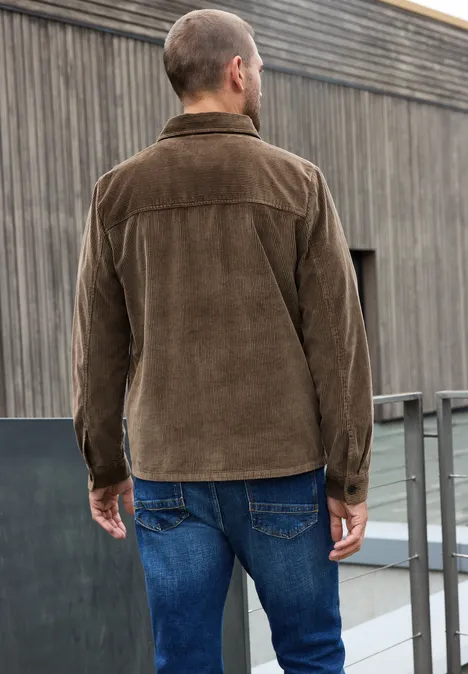 Mann steht mit dem Rücken zur Kamera und trägt eine braune Cordjacke und blaue Jeans.