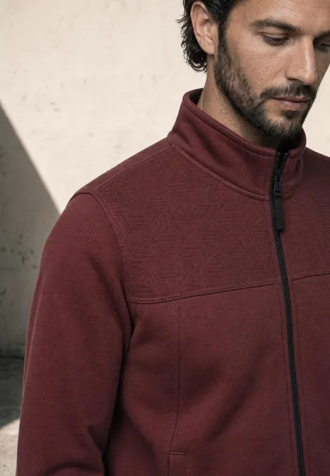 Nahaufnahme eines Mannes in einer burgunderfarbenen Fleecejacke mit Stehkragen und Reißverschluss.