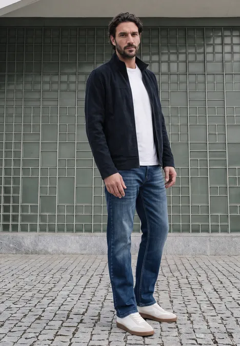 Kurtka z tkaniny sztruksowej z stójką i zamkiem błyskawicznym dark ink blue Mężczyzna w dżinsach, białym t-shircie i ciemnym kardiganie stoi na bruku przed zieloną ścianą z płytek.