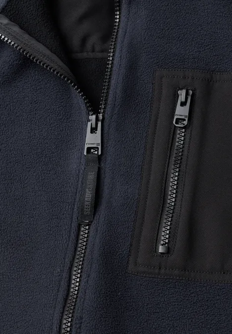 Nahaufnahme einer dunkelblauen Fleecejacke mit Reißverschlüssen und Brusttasche.