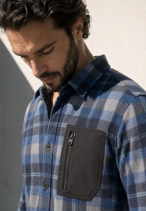 Mann trägt blau-karierte Hemdjacke mit Brusttasche.