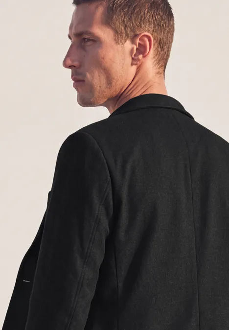 Seitliches Profil eines Mannes mit kurzem Haar in schwarzer Jacke, Blick in Richtung rechts.