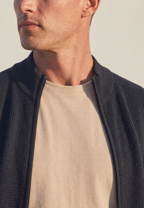 Strickjacke mit Stehkragen und Struktur dark basic blue Ein Mann trägt eine offene schwarze Jacke über einem beigen T-Shirt vor hellem Hintergrund.