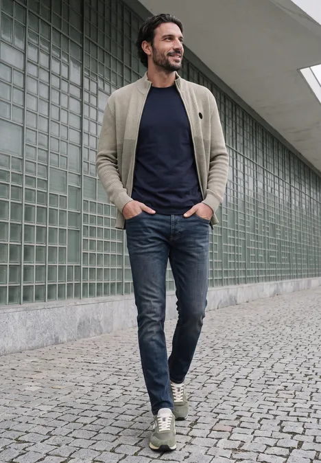 Kardigan z elementami w stylu mouliné i zamkiem błyskawicznym bright beige melange Mężczyzna z brodą w beżowej kurtce, granatowym t-shircie i dżinsach idzie po brukowanym chodniku.