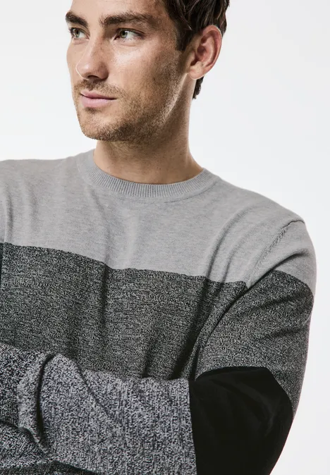 Mann mit grauem Pullover, schaut nach links.