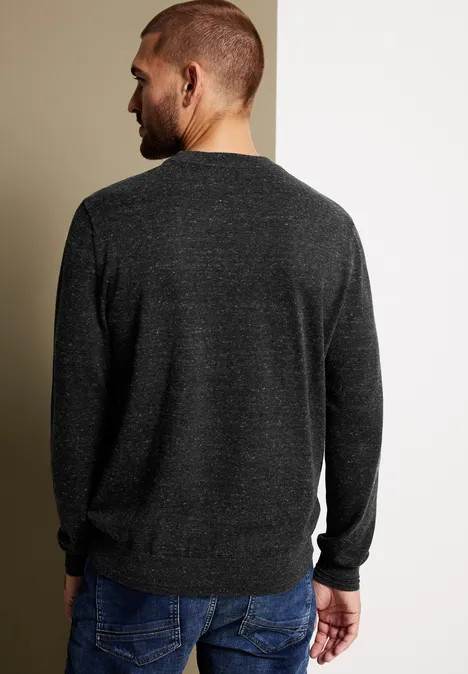 Mann von hinten in dunklem Pullover und Jeans steht vor zweifarbiger Wand.