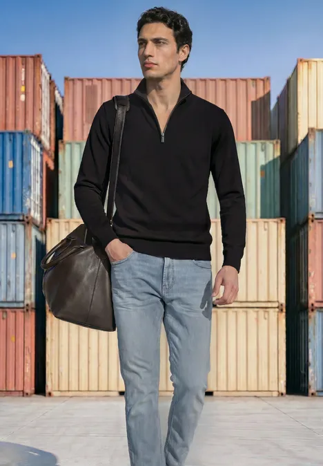Basic Pullover mit Troyerkragen Black Ein lässig gekleideter Mann mit Schultertasche steht vor bunten Schiffscontainern.