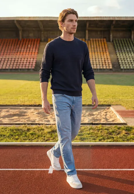 Pullover mit Rundhals und Struktur dark basic blue melange Ein Mann in Jeans und Pullover spaziert über eine Laufbahn im Stadion bei Tageslicht.