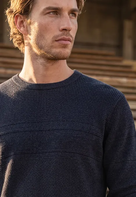 Pullover mit Rundhals und Struktur dark basic blue melange Ein nachdenklicher Mann in dunkelblauem Strickpullover vor einer Holzwand.