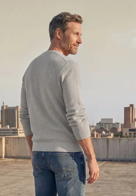 Pullover mit Rundhals und Schulterdetail bright beige melange Ein Mann in grauem Pullover und Jeans steht auf einem Dach und blickt auf die Stadt.