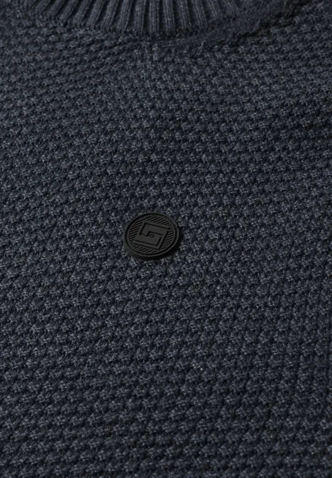 Sweter o strukturze melanżowej dark basic blue melange Zbliżenie na ciemnoniebieski, fakturowany sweter z małym, okrągłym czarnym logotypem na środku.
