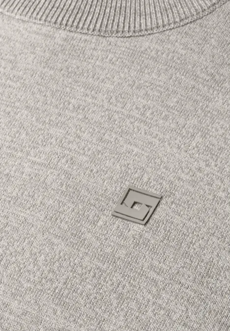Grauer Strickpullover mit kleinem Metall-Logo in G-Form auf der Brust.