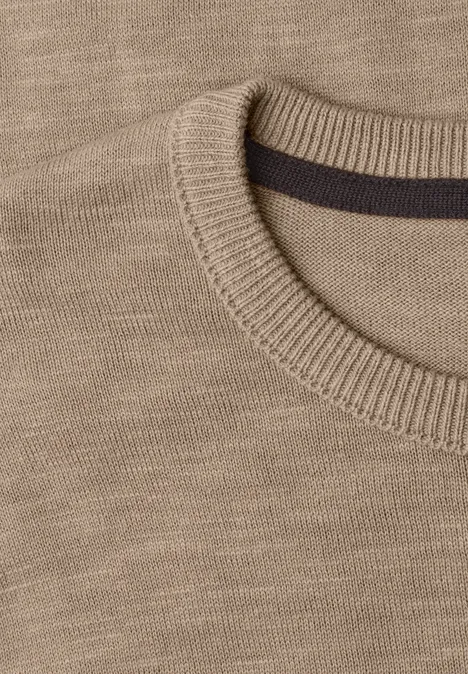 Nahaufnahme eines beigen Strickpullovers mit Rundhalsausschnitt und gerippter Kante
