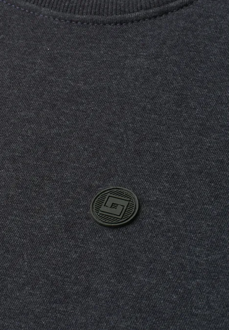 Dunkelgraues Shirt mit kleinem, rundem, schwarzem Logo-Patch mittig.