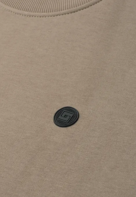 Beiges Sweatshirt mit Rundhalsausschnitt und kleinem schwarzem Logo-Patch auf der Brust.