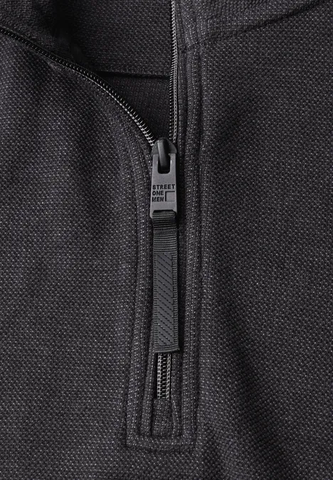 Sweatshirt à col montant et fermeture zip Black Nahaufnahme eines schwarzen Reißverschlusses auf grob gewebtem Textil.