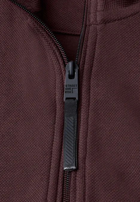Sweatshirt à col montant et fermeture zip maroon brown Nahaufnahme eines dunkelroten Reißverschlusses an einem Kleidungsstück.