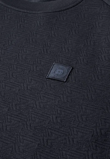 Schwarzes, strukturiertes T-Shirt mit geometrischem Muster und mittig angebrachtem Logo-Patch.