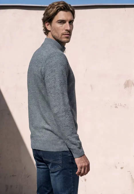 Pullover mit Troyerkragen und Struktur vintage blue Ein Mann mit hellbraunen Haaren trägt grauen Pullover und Jeans, steht vor rosa Wand und schaut über die Schulter.