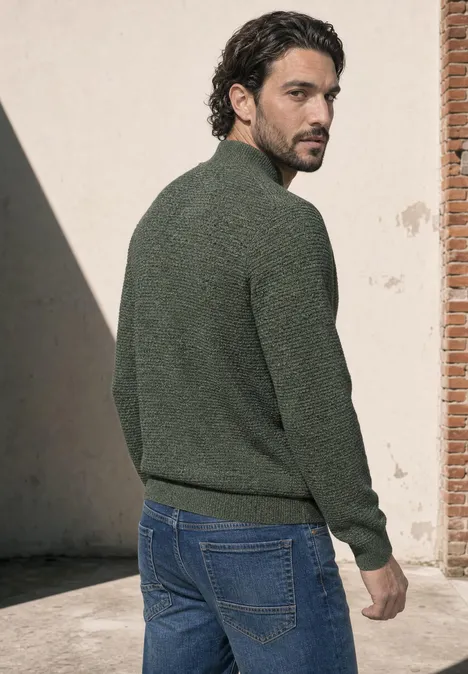 Pullover mit Troyerkragen und Struktur willow green Ein Mann im grünen Pullover und Jeans steht draußen und blickt über die Schulter.