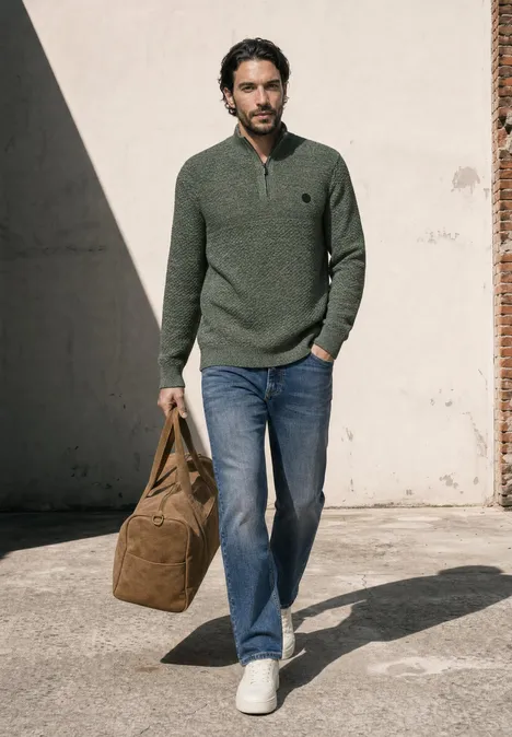 Pullover mit Troyerkragen und Struktur willow green Ein Mann in grünem Pullover und Jeans trägt eine Tasche und geht an einer Hauswand entlang.