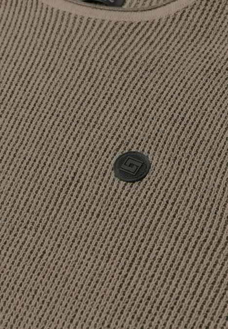 Vue rapprochée d'un vêtement en maille brun clair avec encolure ronde et petit bouton logo sombre.