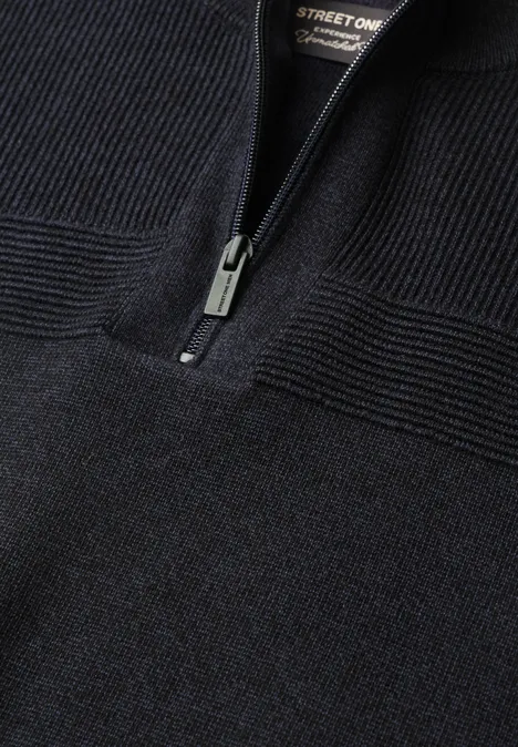 Schwarzer Strickpullover mit halbem Reißverschluss und markanter Rippstruktur am Ausschnitt.