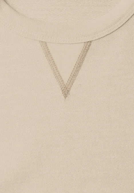 Nahaufnahme eines beigen Sweatshirt-Ausschnitts mit V-förmiger Ziernaht