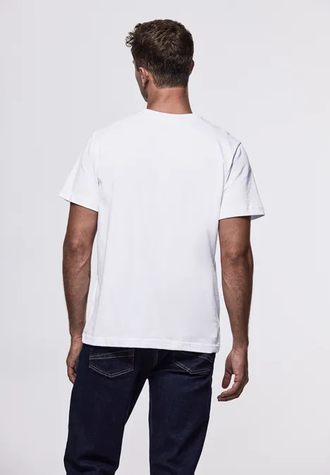 Mann von hinten in weißem T-Shirt und Jeans vor weißem Hintergrund.