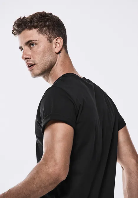 Junger Mann mit kurzem Haar, schwarzem T-Shirt, blickt über die Schulter.