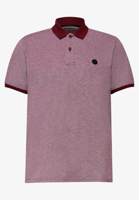 Un polo rose clair chiné avec un col et des bordures foncés, patte de boutons et petit logo noir sur la poitrine.