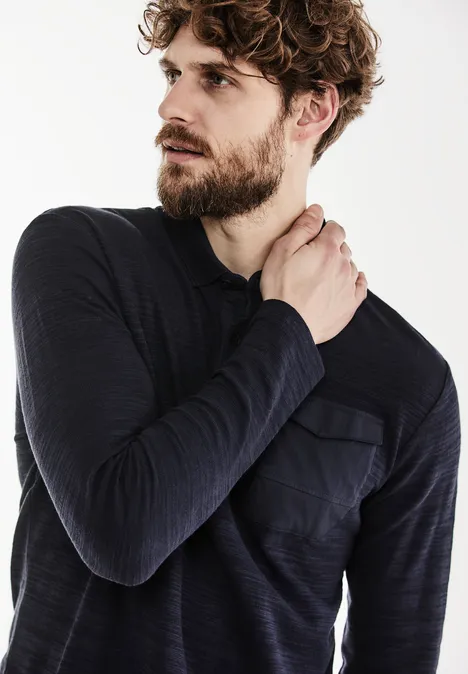 Mann mit Bart trägt dunkles Langarmshirt und blickt nach links.
