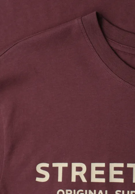 Nahaufnahme eines bordeauxroten T-Shirts mit weißer Aufschrift 'STREET'.