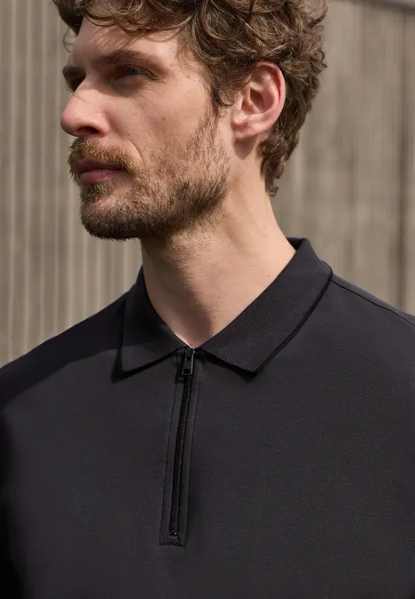 Polo met korte mouwen en ritssluiting dark ink blue Ein Mann trägt ein schwarzes Polo-Shirt mit Reißverschluss, Gesicht unkenntlich, vor neutralem Hintergrund.