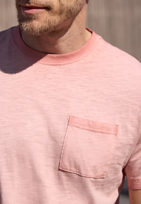 Close-up van een man met een roze T-shirt en borstzakje