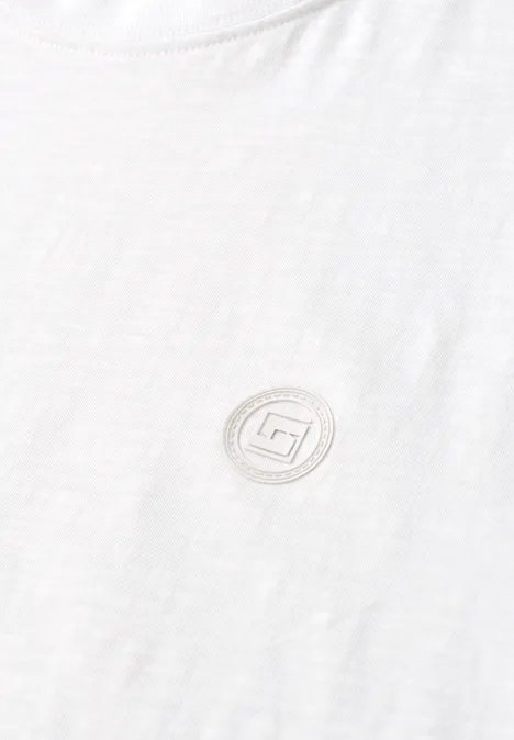 Weißes T-Shirt mit rundem, dezentem Logo in Salbeigrün auf der Brust.