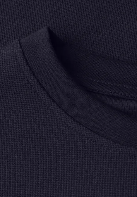 Close-up van een zwarte, fijngebreide ronde hals van een shirt