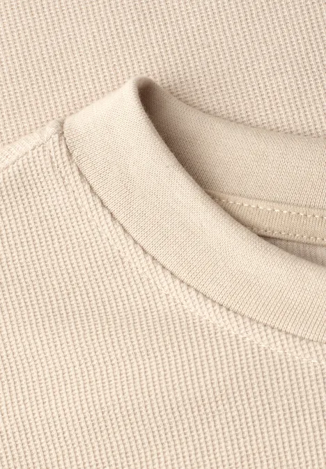 Close-up van een beige ronde hals en een fijnkorrelige katoenen tricot stof.