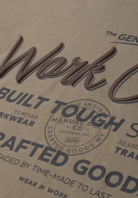 Nahaufnahme eines beigen T-Shirts mit Vintage-Aufdruck: 'Work Co', 'Built Tough', 'Crafted Goods'.